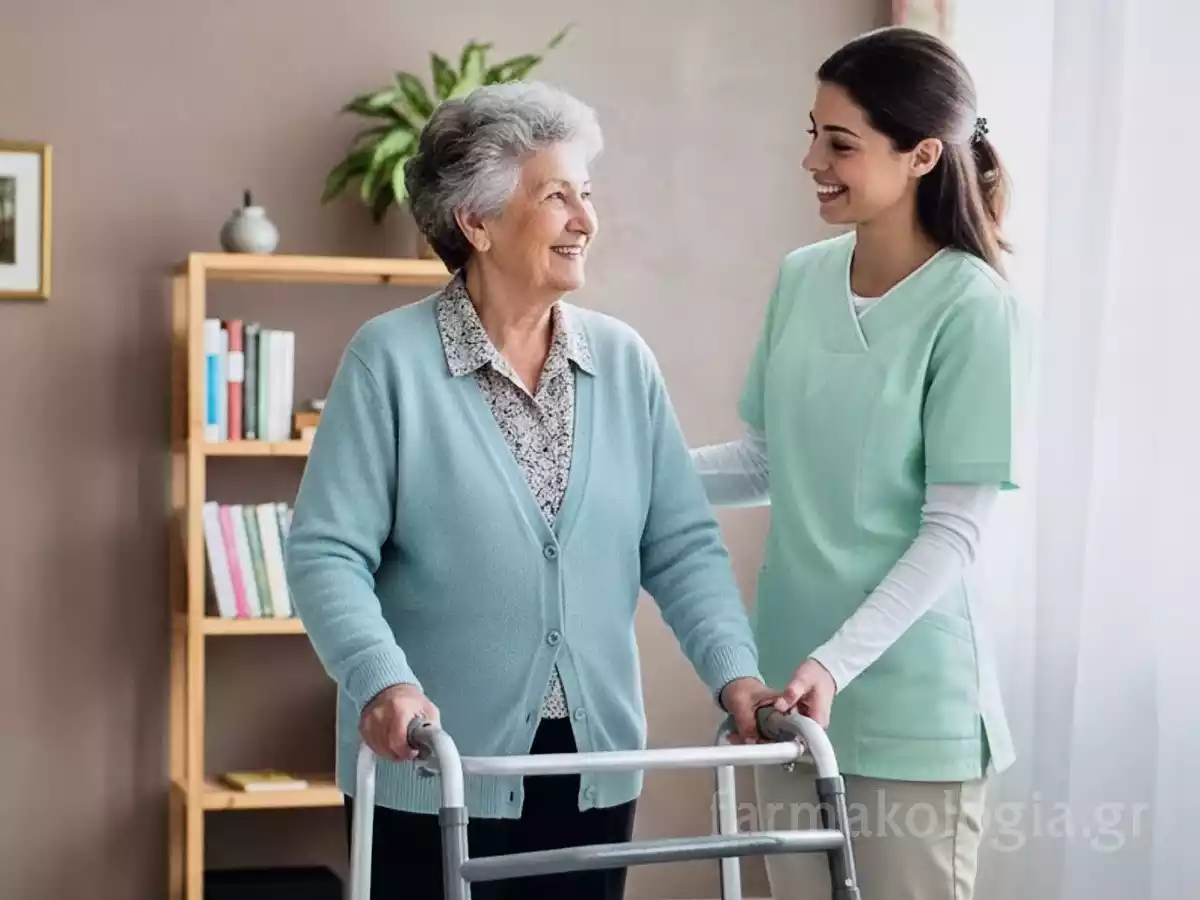Φροντιστής βοηθά γυναίκα με περιπατητήρα, υπογραμμίζοντας τα κινητικά συμπτώματα του Πάρκινσον.